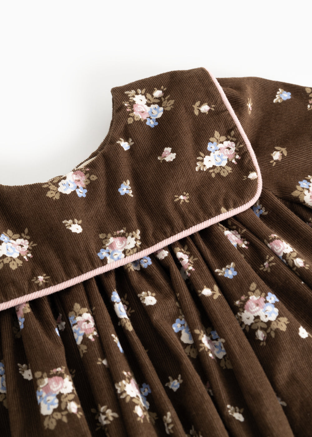 A dress with a floral print, chest and round collar, and a light edge around the opening.