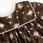 A dress with a floral print, chest and round collar, and a light edge around the opening.