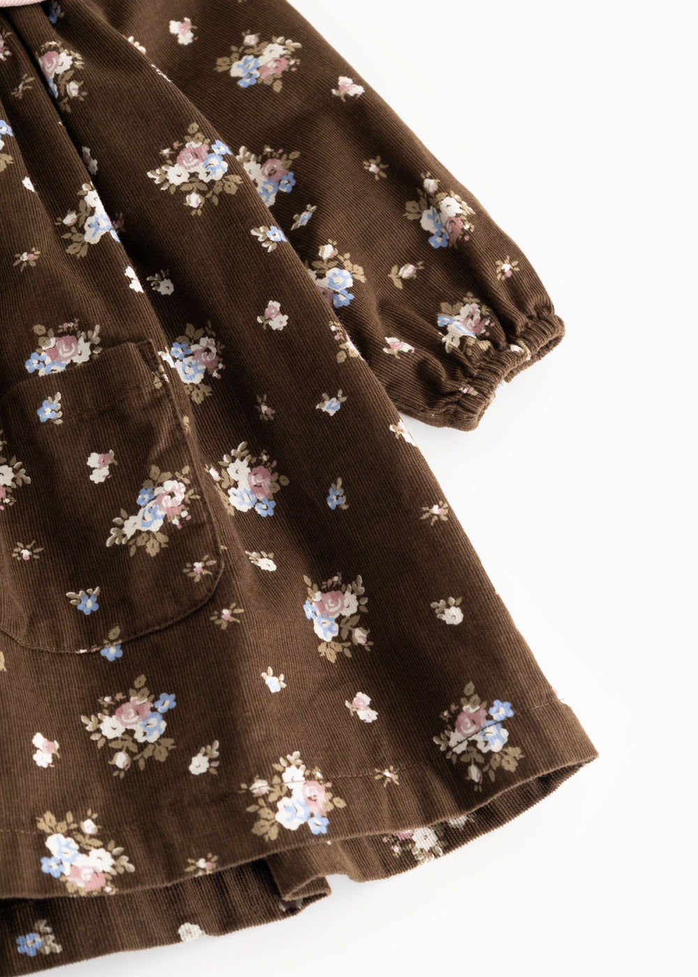 Floral dress in dark brown fabric with small multicolored flowers and a ribbed edge at the sleeve hem.