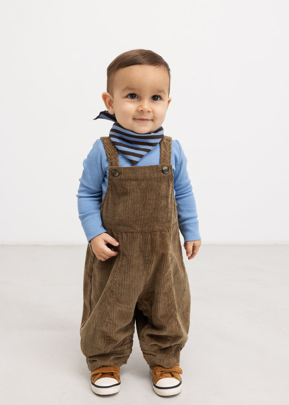 Riri B trousers in dark brown velvet‑ribbed fabric with front pockets and suspenders.