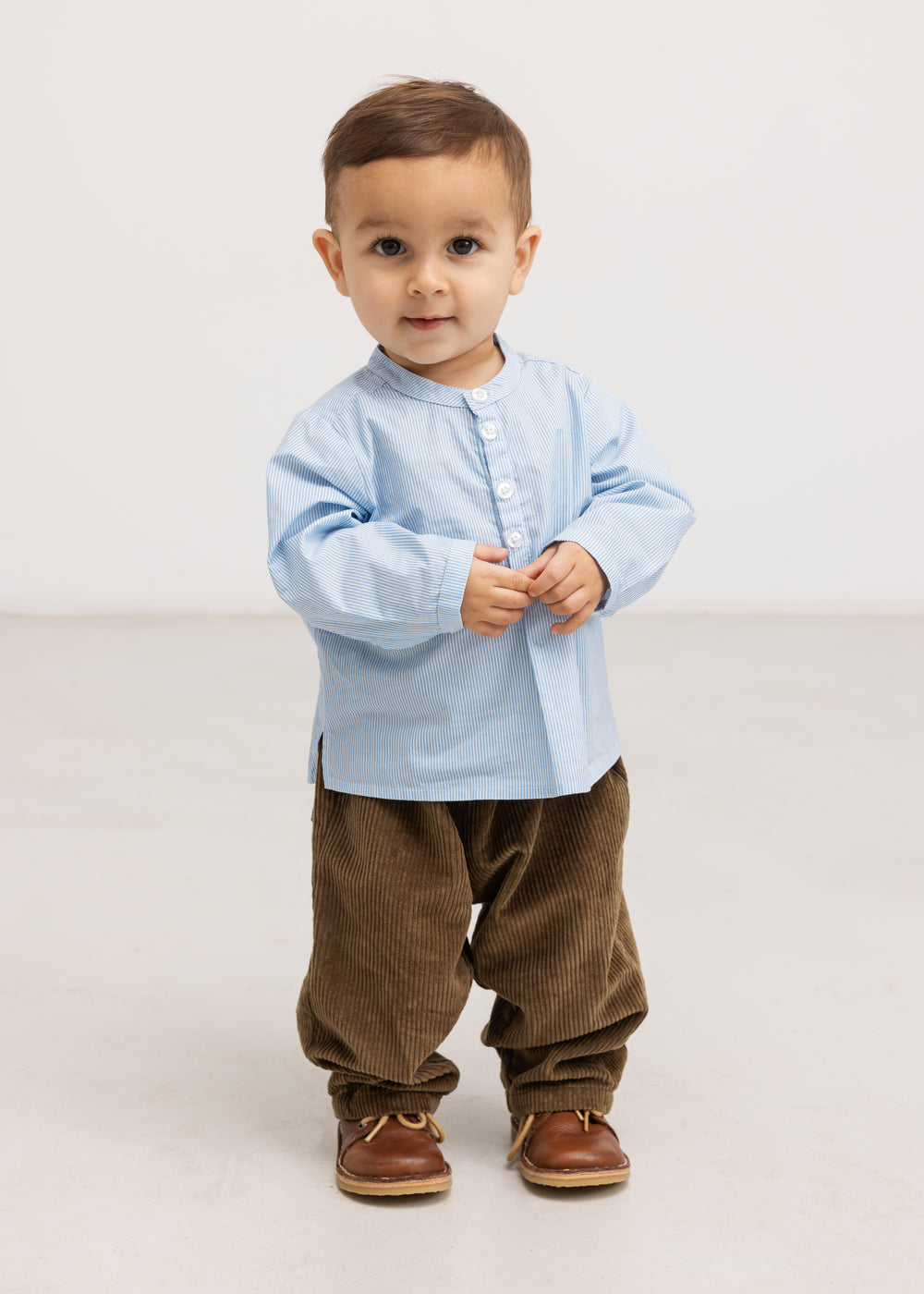 Baby leggings in dark brown velvet with elastic at the waist, standing.