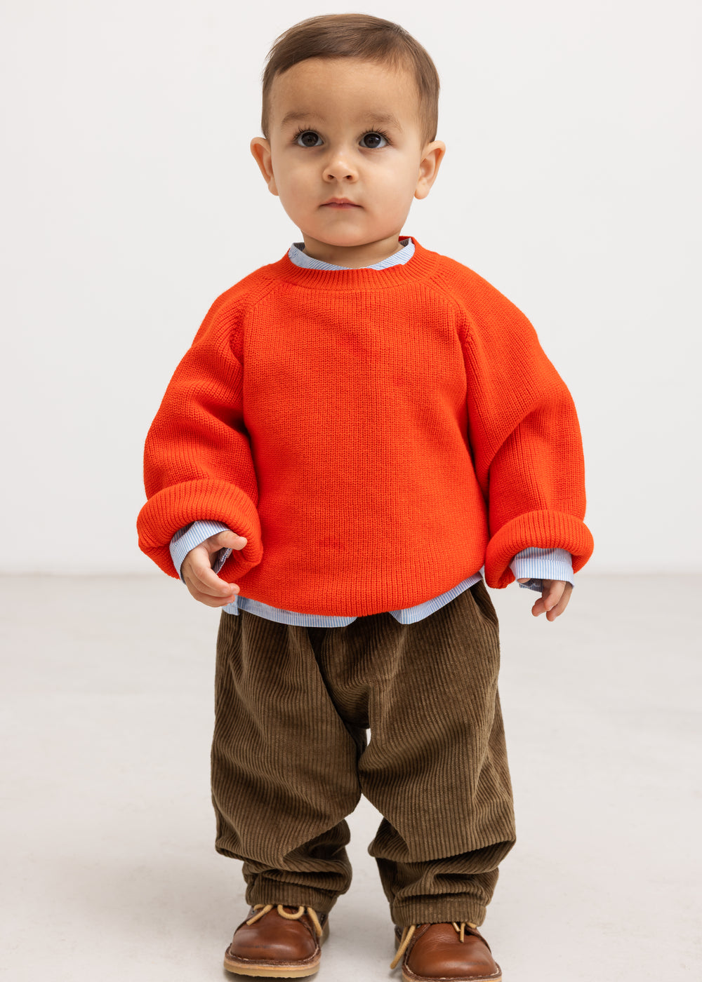 Baby ones in dark brown velvet with elastic at the waist, seen from the front.