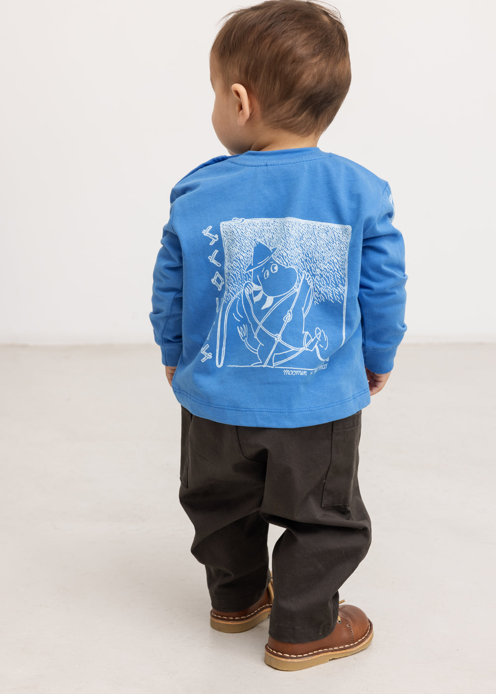 Blue long-sleeve blouse with a large back motif, seen from behind on a child.