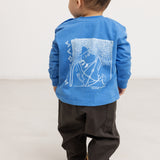 Blue long-sleeve blouse with a large back motif, seen from behind on a child.
