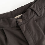 Dark trousers with belt straps and a round button closure at the waist.