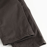 Dark pants with slanted seam and cuff at the leg opening.