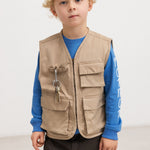 Sand-colored children's vest with snap pockets and zipper, worn over a blue blouse