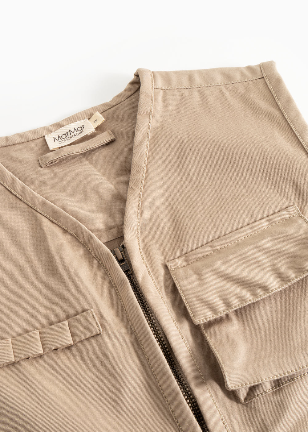 Beige children's vest with V-neck, zipper and flap pockets, and inner label.