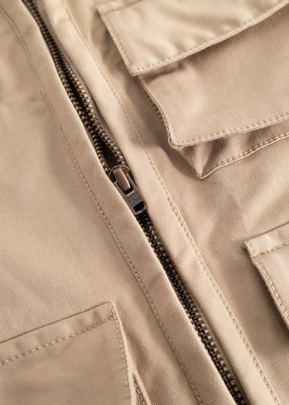 Sand-colored children's vest with a strong black zipper and visible seams.