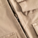 Sand-colored children's vest with a strong black zipper and visible seams.