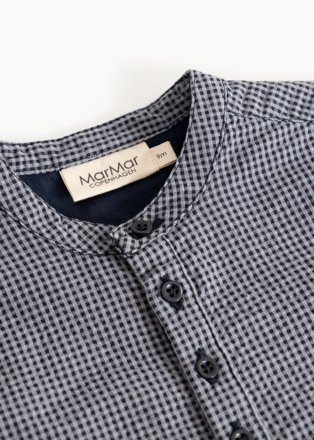Short baby nets with a button pole and MarMar brand at the neck, dark dove blue checkered.