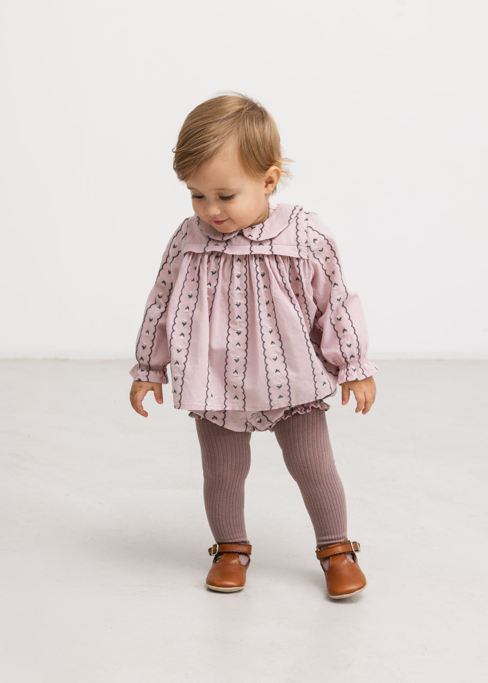 Pink baby blouse on model with long sleeves and front button closure.