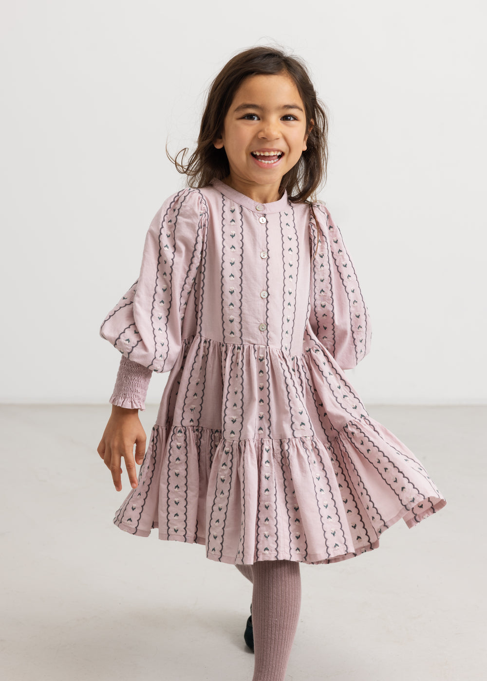 A dress in dusty lilac with a pleated skirt, puff sleeves, and floral details.