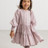 A dress in dusty lilac with a pleated skirt, puff sleeves, and floral details.