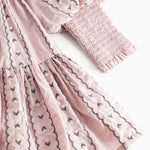 Dress the dress in dusty lilac with floral embroidery and long puff sleeves.