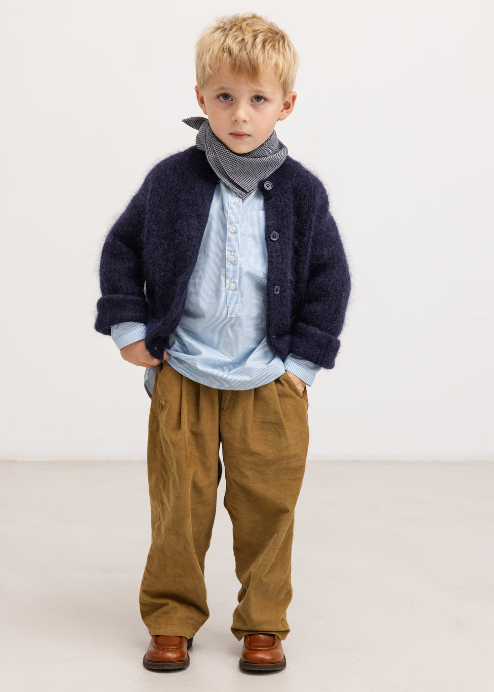 Light blue striped shirt with button closure under dark cardigan.