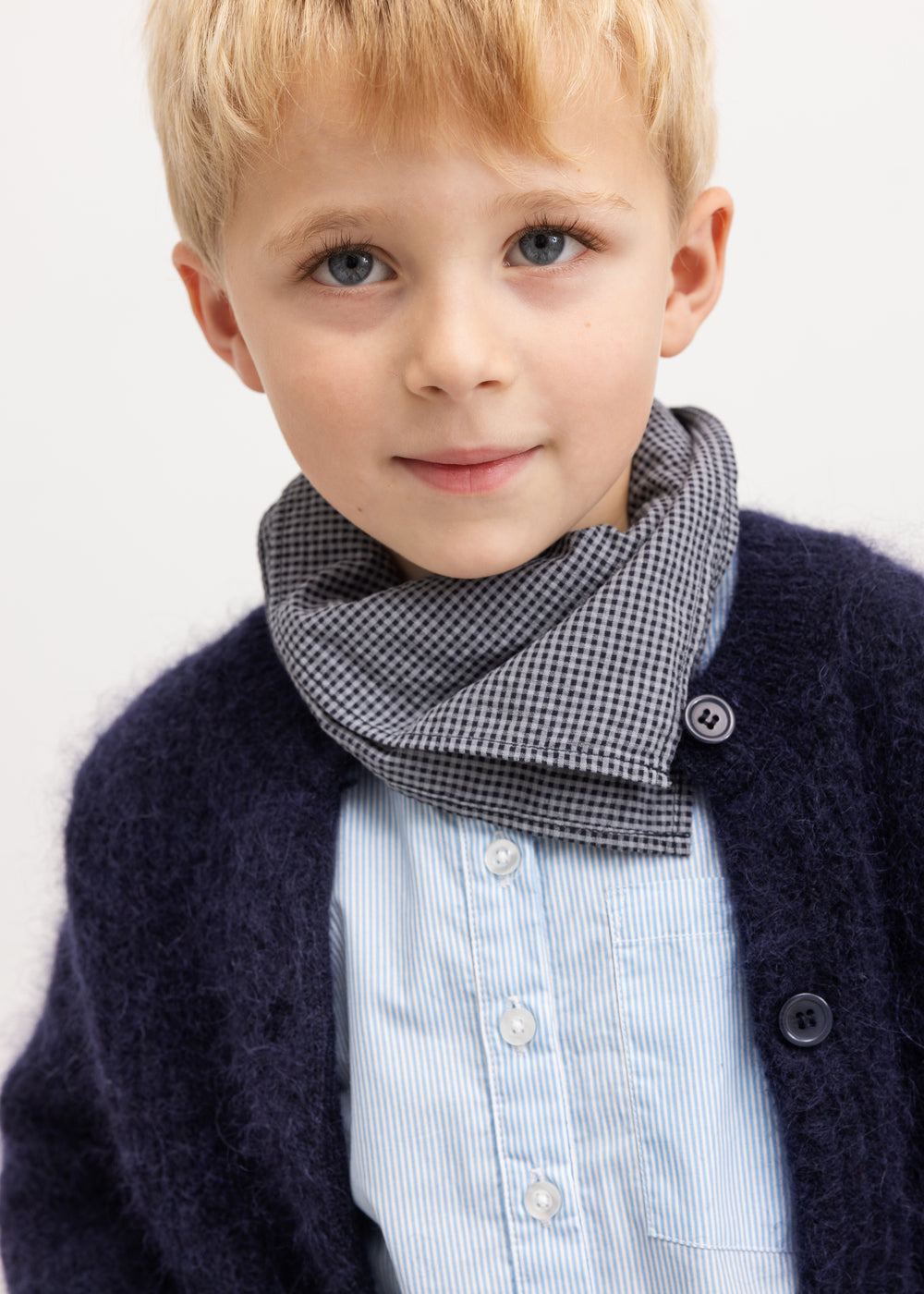 Light blue striped shirt with visible buttons under a dark cardigan.
