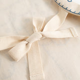 Natural-colored apron with tie strap and fabric bow in front, visible textures
