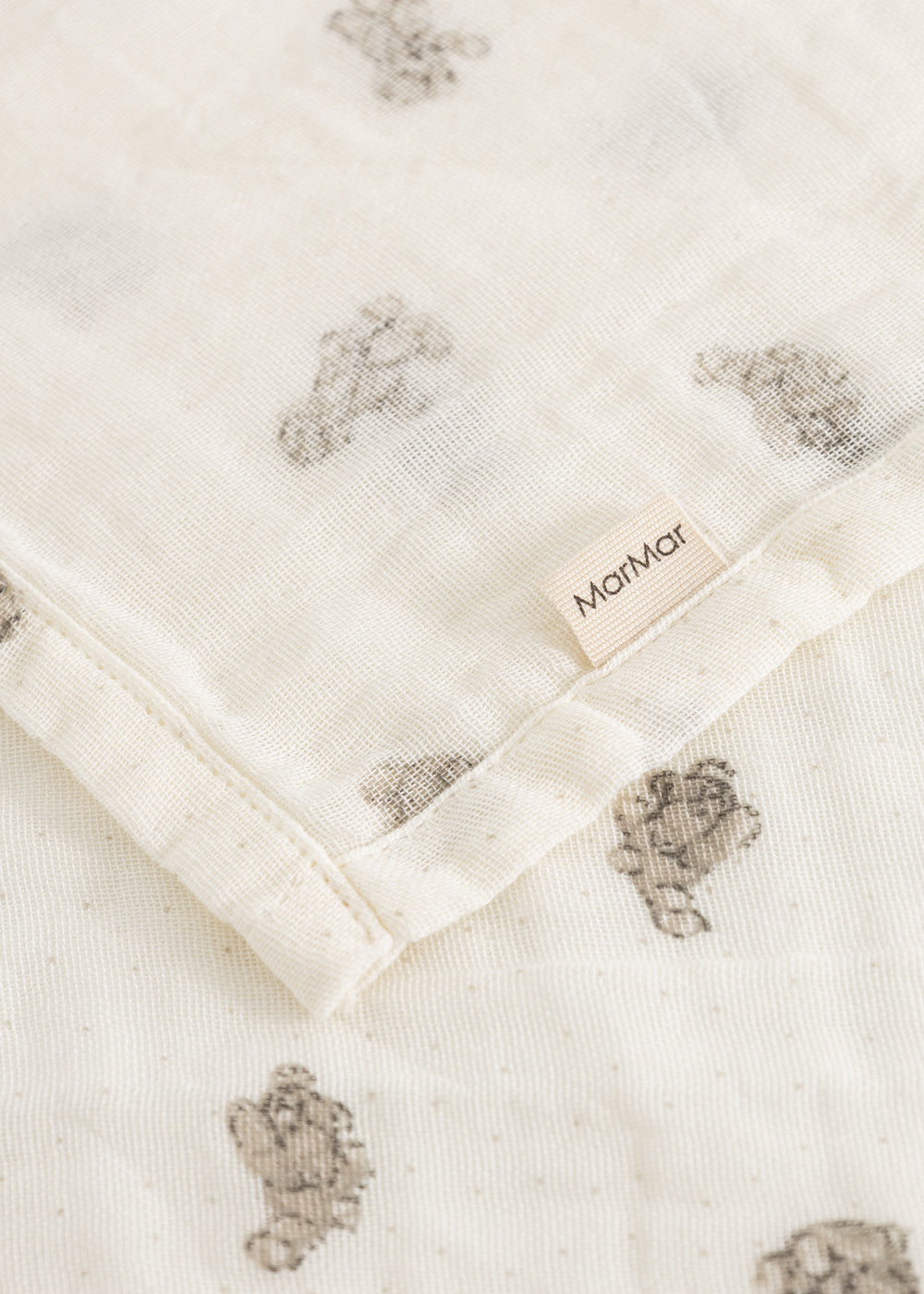 Soft cream-colored cotton with small teddy bear print and visible edge.