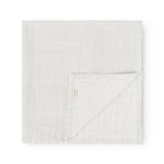 Square fabric blanket with small black dots, folded with a hidden edge line.