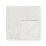 Square fabric blanket with small black dots, folded with a hidden edge line.