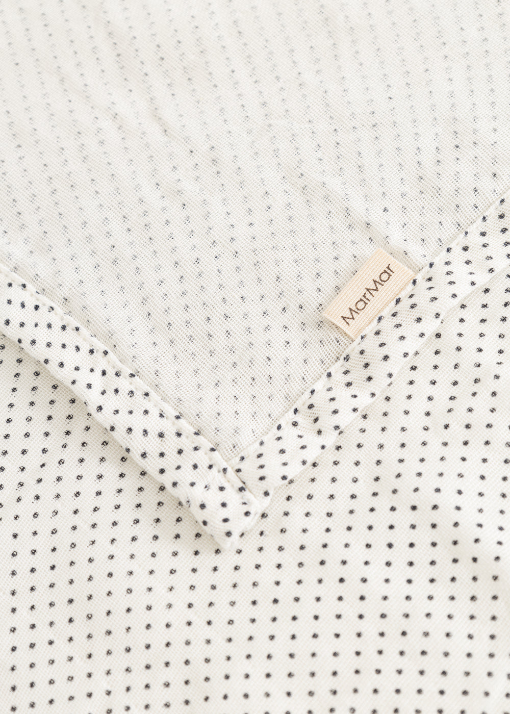 Cream rug with small black dots and a marMar label at the edge.