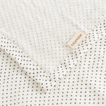 Cream rug with small black dots and a marMar label at the edge.