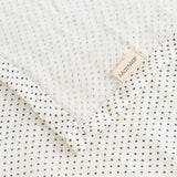 Cream rug with small black dots and a marMar label at the edge.
