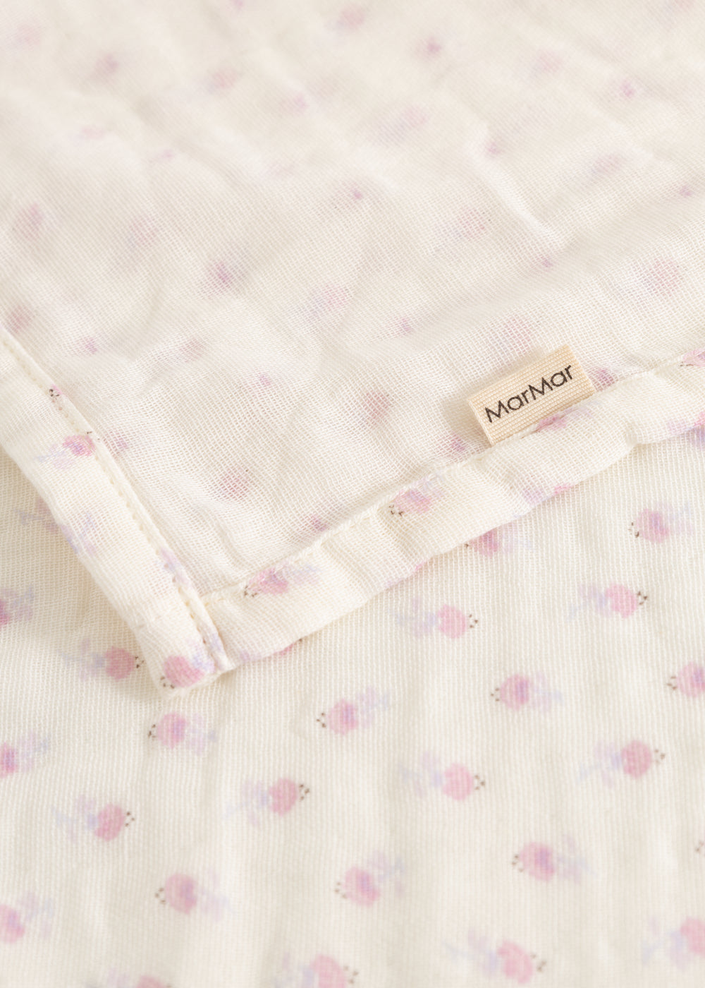 Cream-colored baby onesie with small pink flowers, ruffle edge, and MarMar brand.