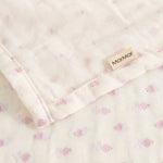Cream-colored baby onesie with small pink flowers, ruffle edge, and MarMar brand.