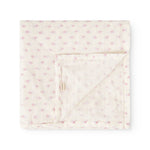 Baby swaddle folded and fastened with a strap, cream-colored with small pink flowers.