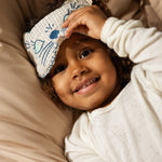 Sleep mask with checkered white fabric and blue embroidery on children's eyes.