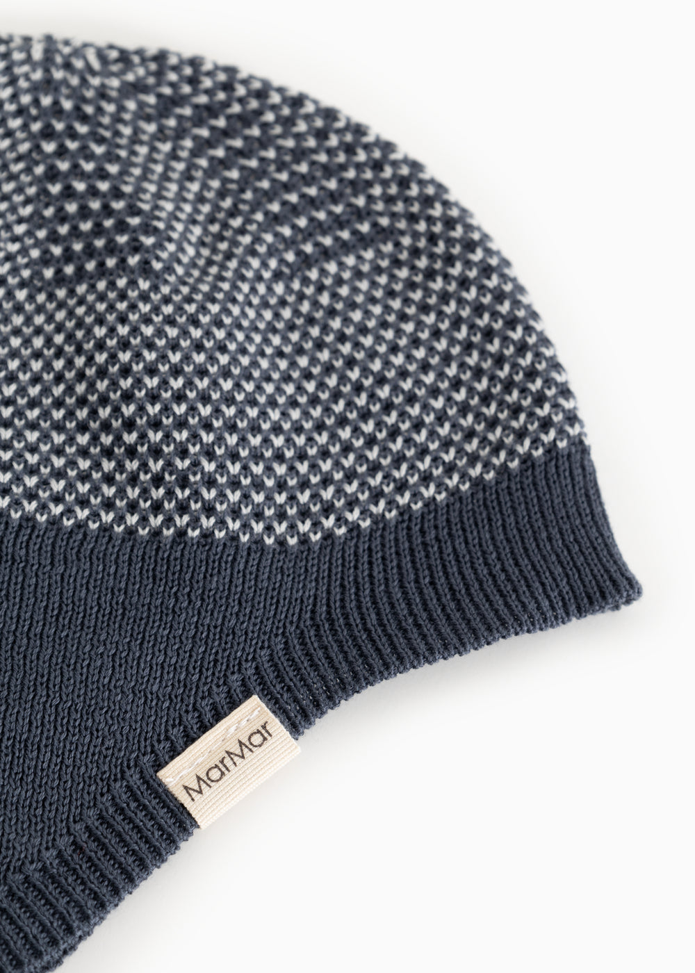 Details of a blue striped hat in a knitted pattern with ribbed edge and side label.