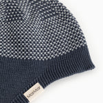 Details of a blue striped hat in a knitted pattern with ribbed edge and side label.