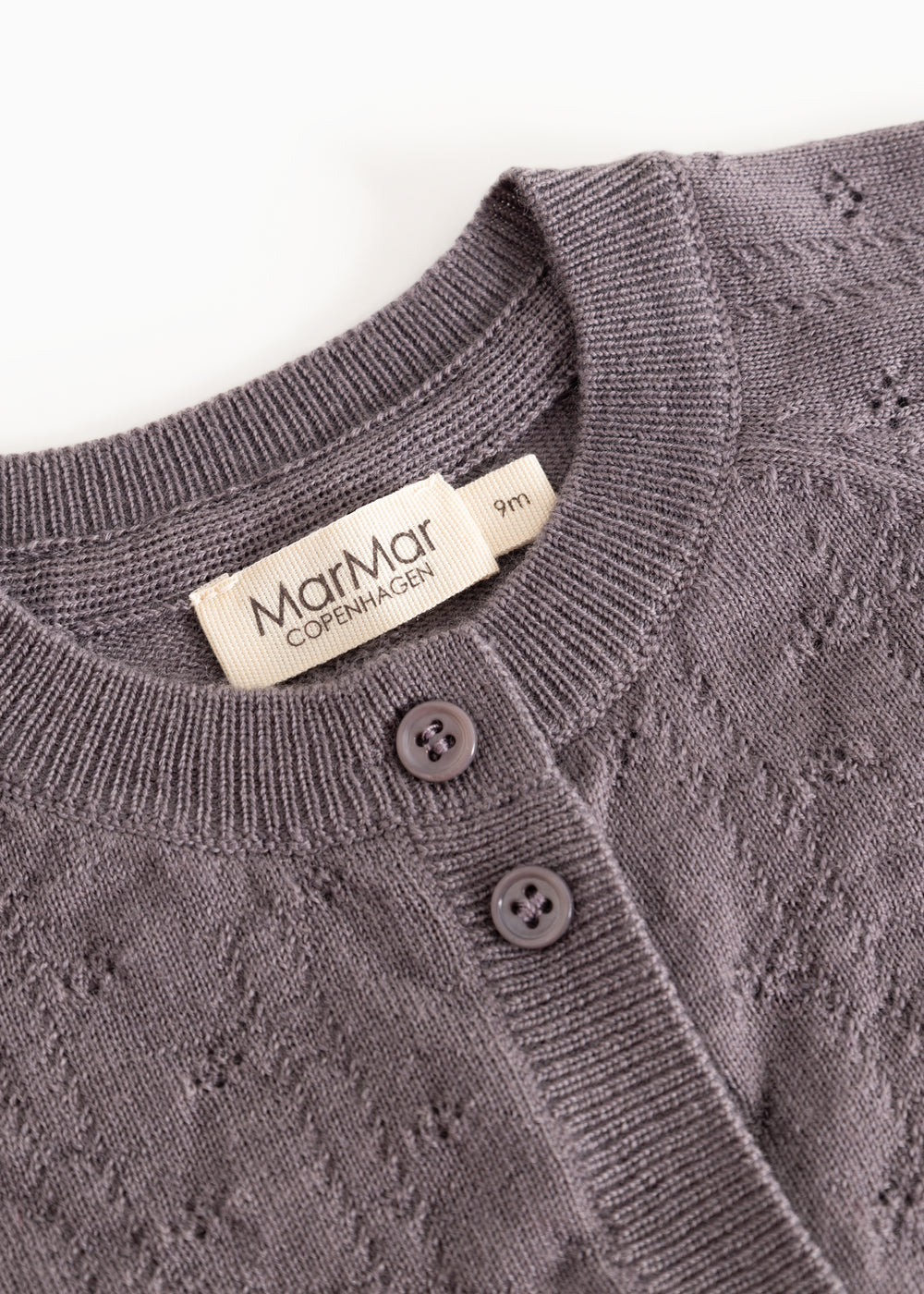 Dark purple knitted cardigan with ribbed edge, two buttons and a label.