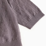 Dark purple knitted cardigan with ribbed edge and pattern in the fabric.