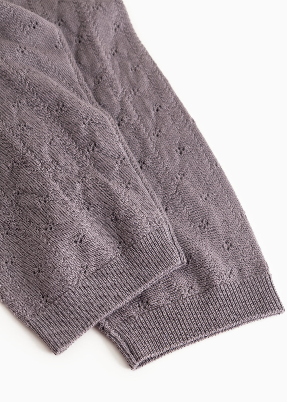 Dark purple knit trousers with ribbed edge and fine polka dot pattern at the leg opening.