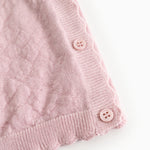 Pink knit cardigan with buttons and ribbed edge at the bottom and sleeves.