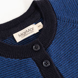 Blue knitted cardigan with black rib collar, two buttons and label.