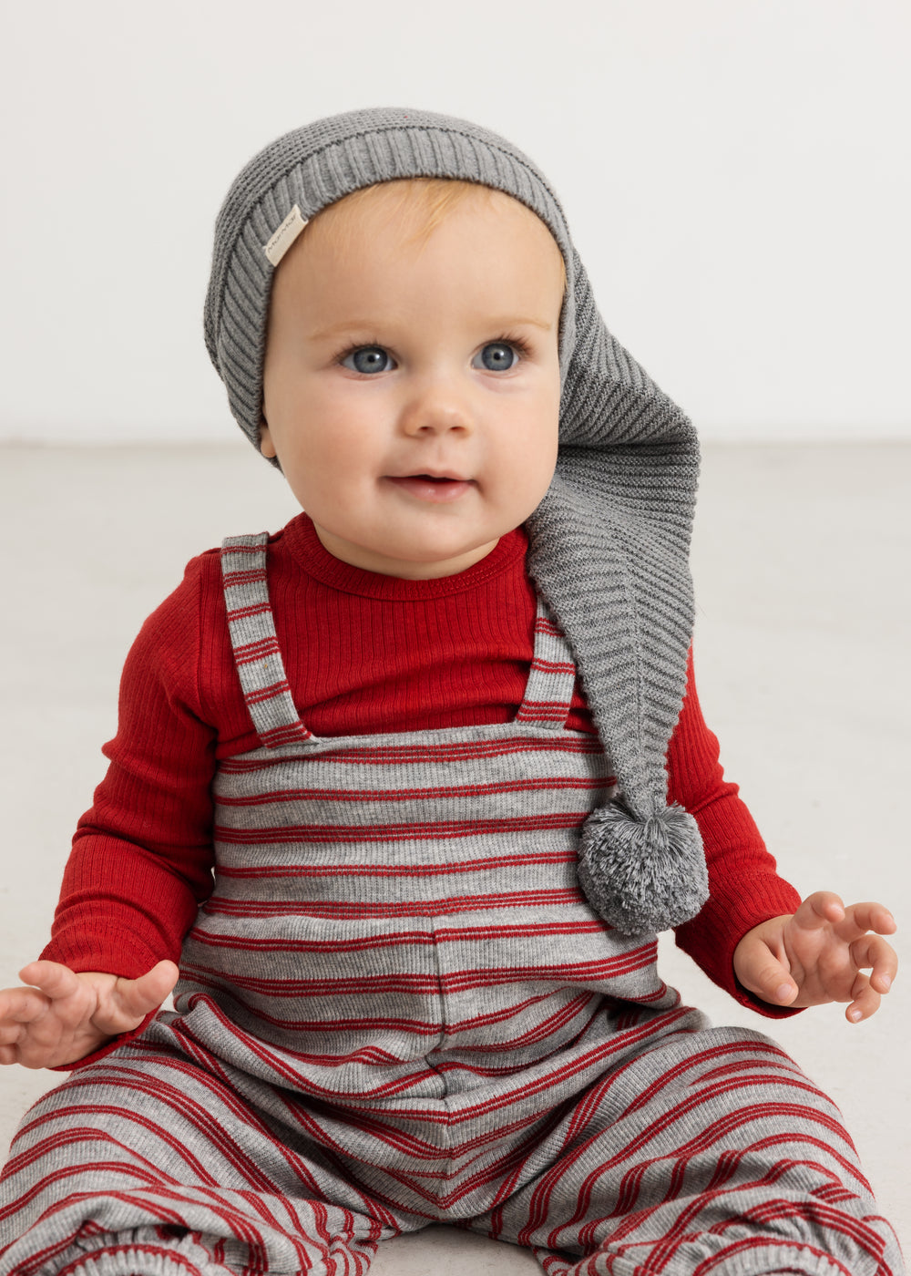 Gray and red striped romper with wide straps, worn by baby