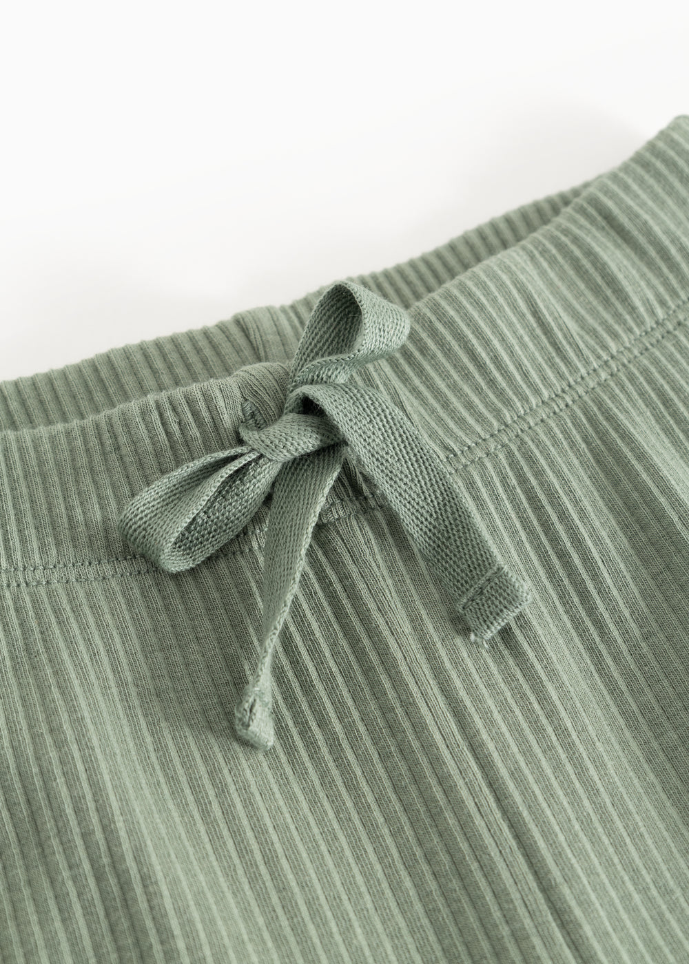 Detail of green waistband on ribbed knit pants with elastic and drawstring