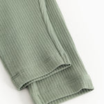Bottom edge of green ribbed knit pants with elastic cuff