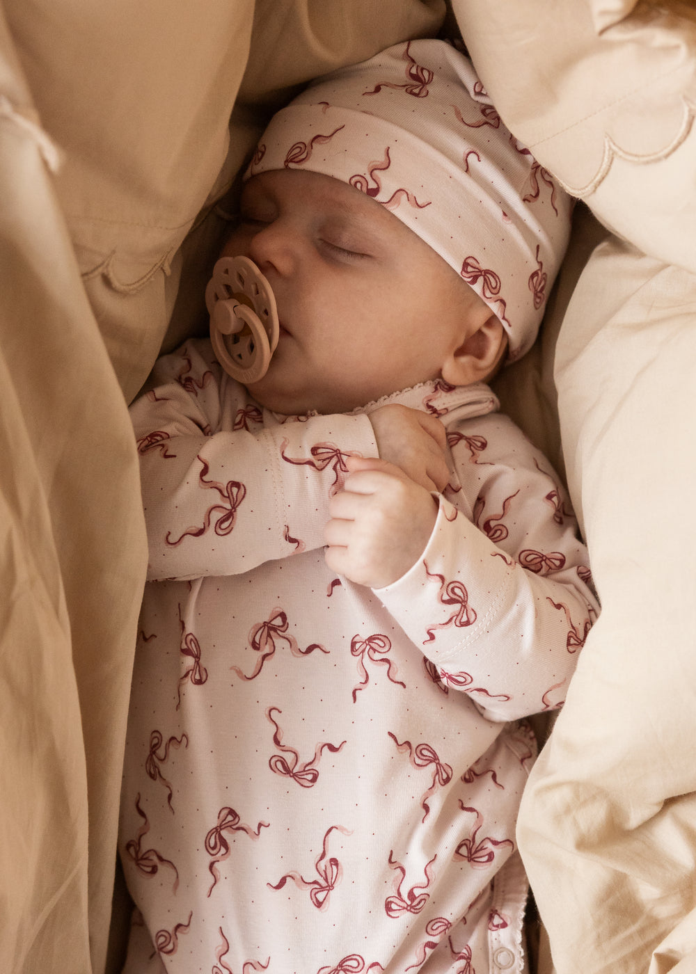 Belita bodystocking with bow print, worn by sleeping baby
