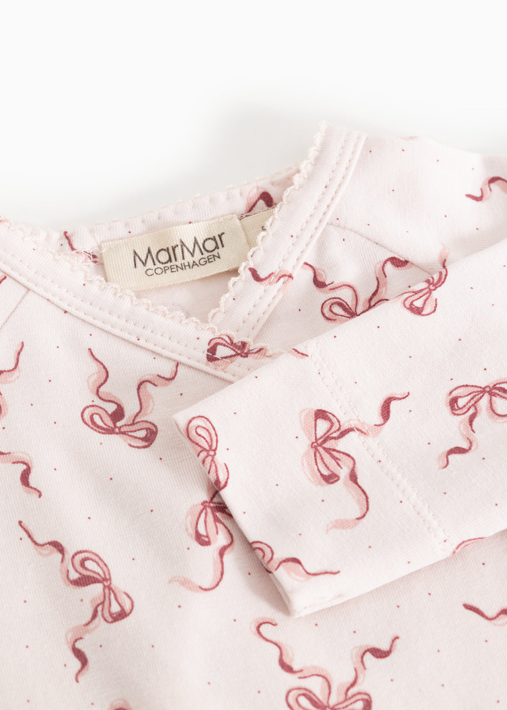 Neckline on light jumpsuit with red bow pattern and label