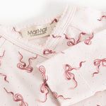 Neckline on light jumpsuit with red bow pattern and label