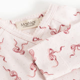 Neckline on light jumpsuit with red bow pattern and label