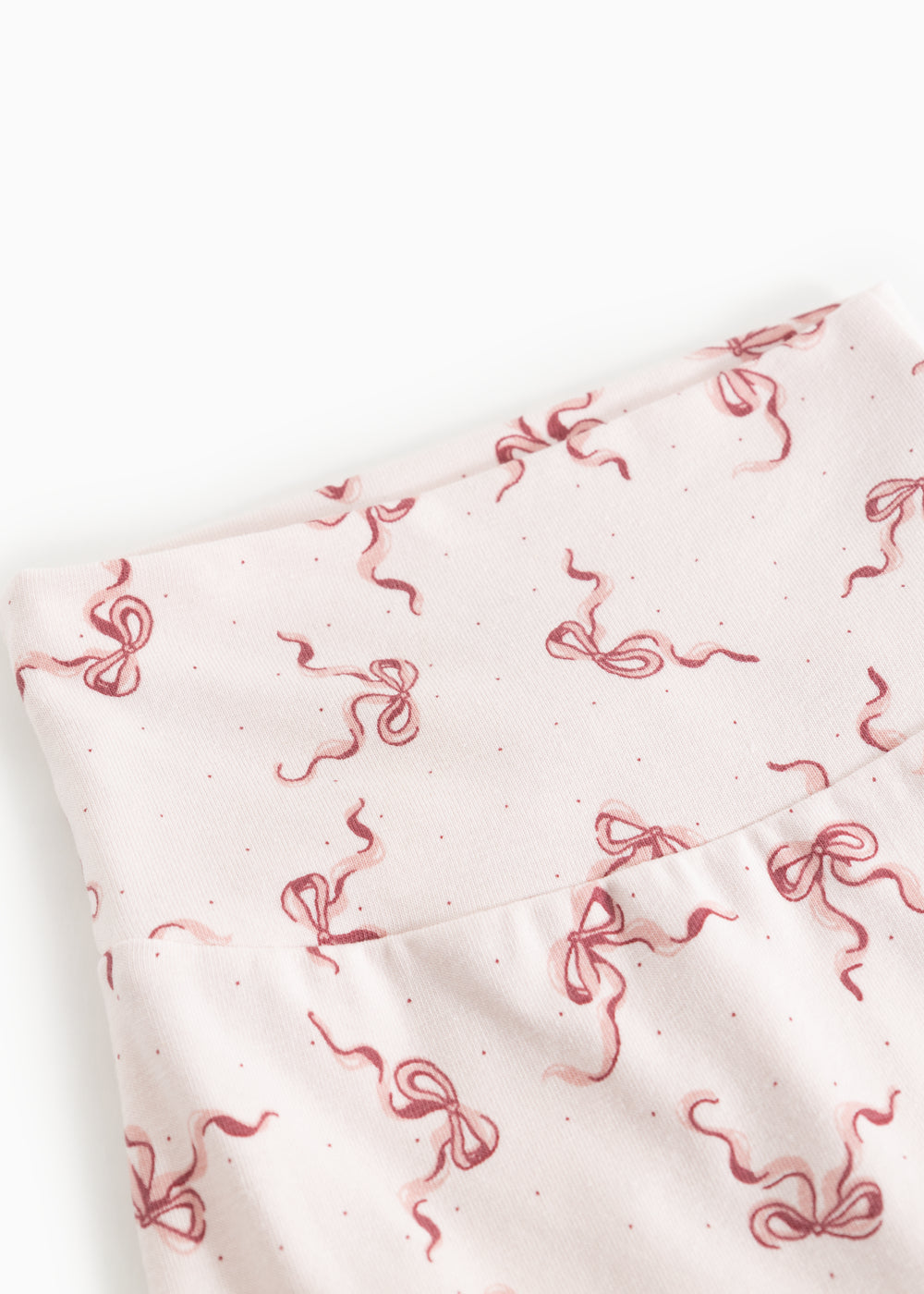 Close-up of baby pants: white fabric with red bow print