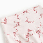 Detail of light pants with a red bow pattern in a dense repeat