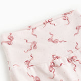 Detail of light pants with a red bow pattern in a dense repeat