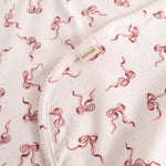 Carpet with bow pattern, reddish-pink on light background, edge and label
